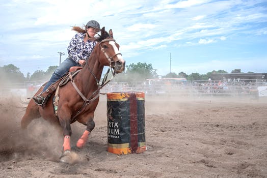 Dynamic barrel racing scene capturing horse and rider in an outdoor rodeo setting.